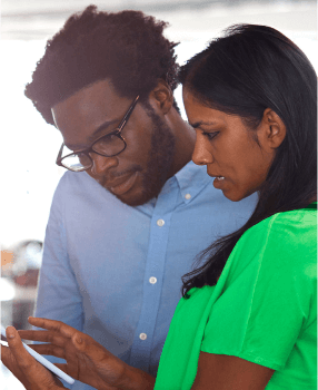 Two team members discussing business while looking at a tablet.